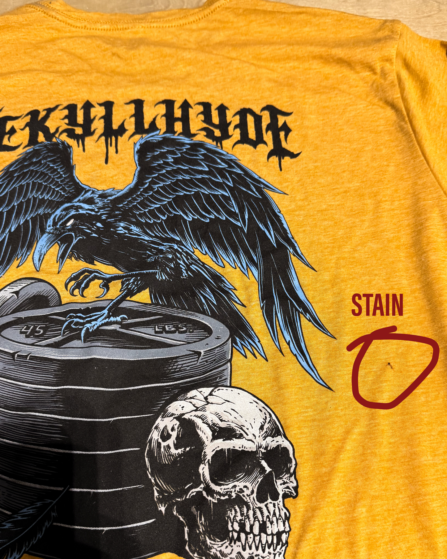 Flat lay of Jekyllhyde Raven tshirt with small stain on the mid back area.