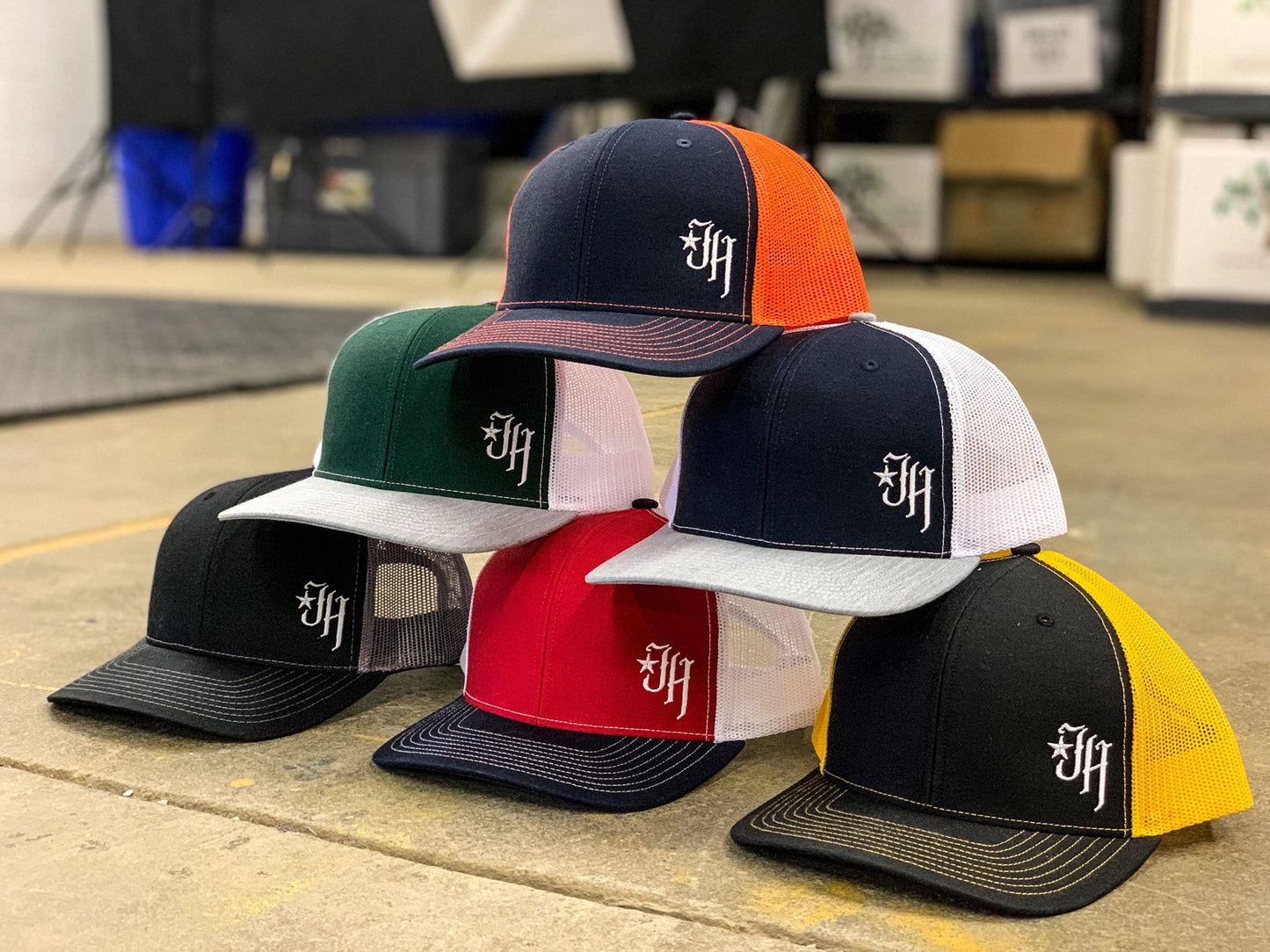 6 trucker hats stacked in a pyramid.