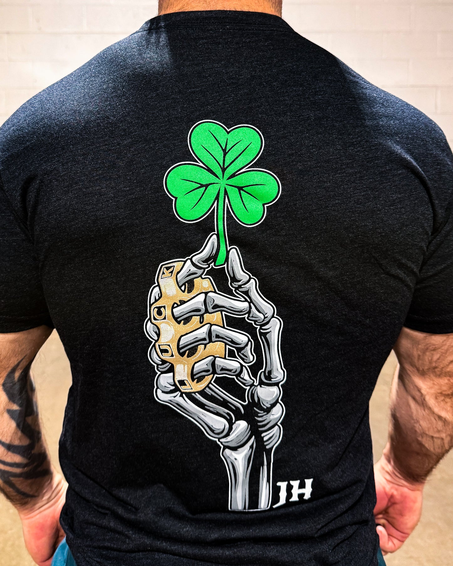 Black t-shirt with a skeleton hand holding a shamrock design on the back.