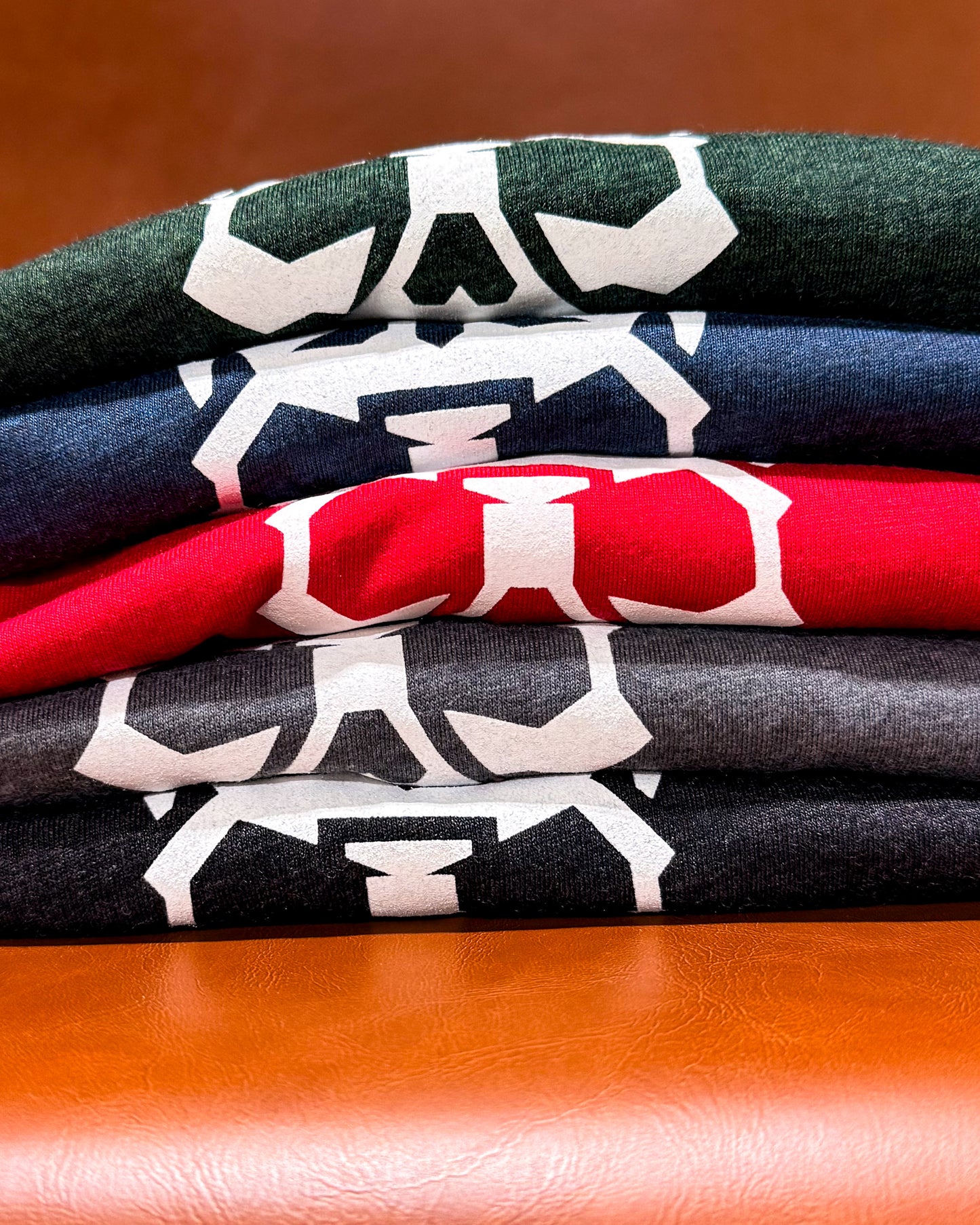 A stack of different colored t-shirts on chair. 