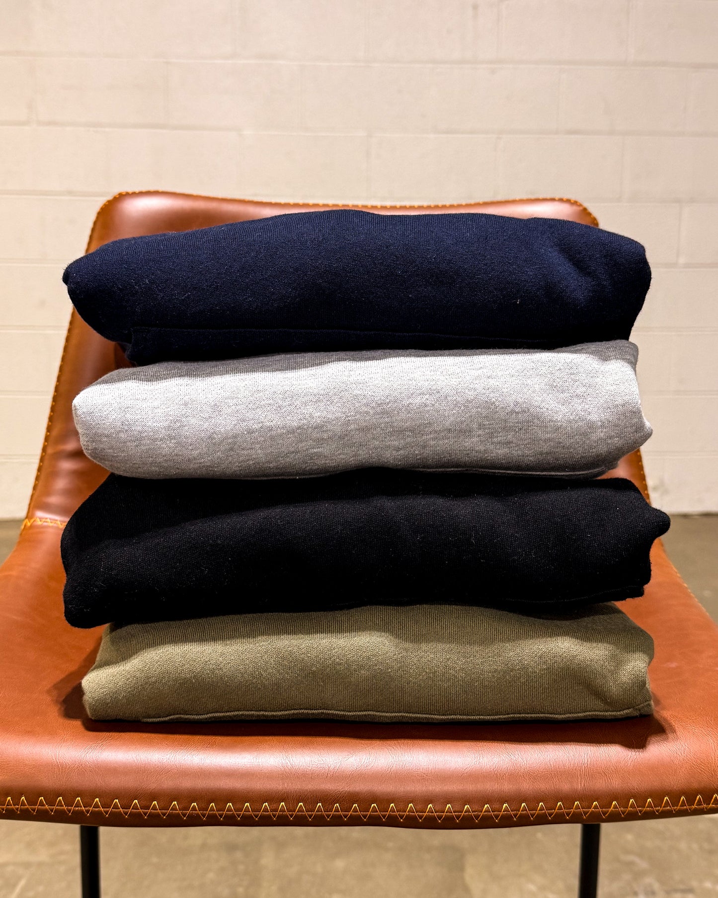 A stack of hoodies on a chair.