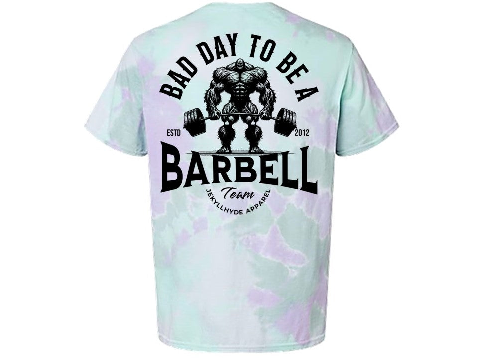 T-shirt with 'Bad Day to Be a Barbell' design on a light green and purple tie-dye background