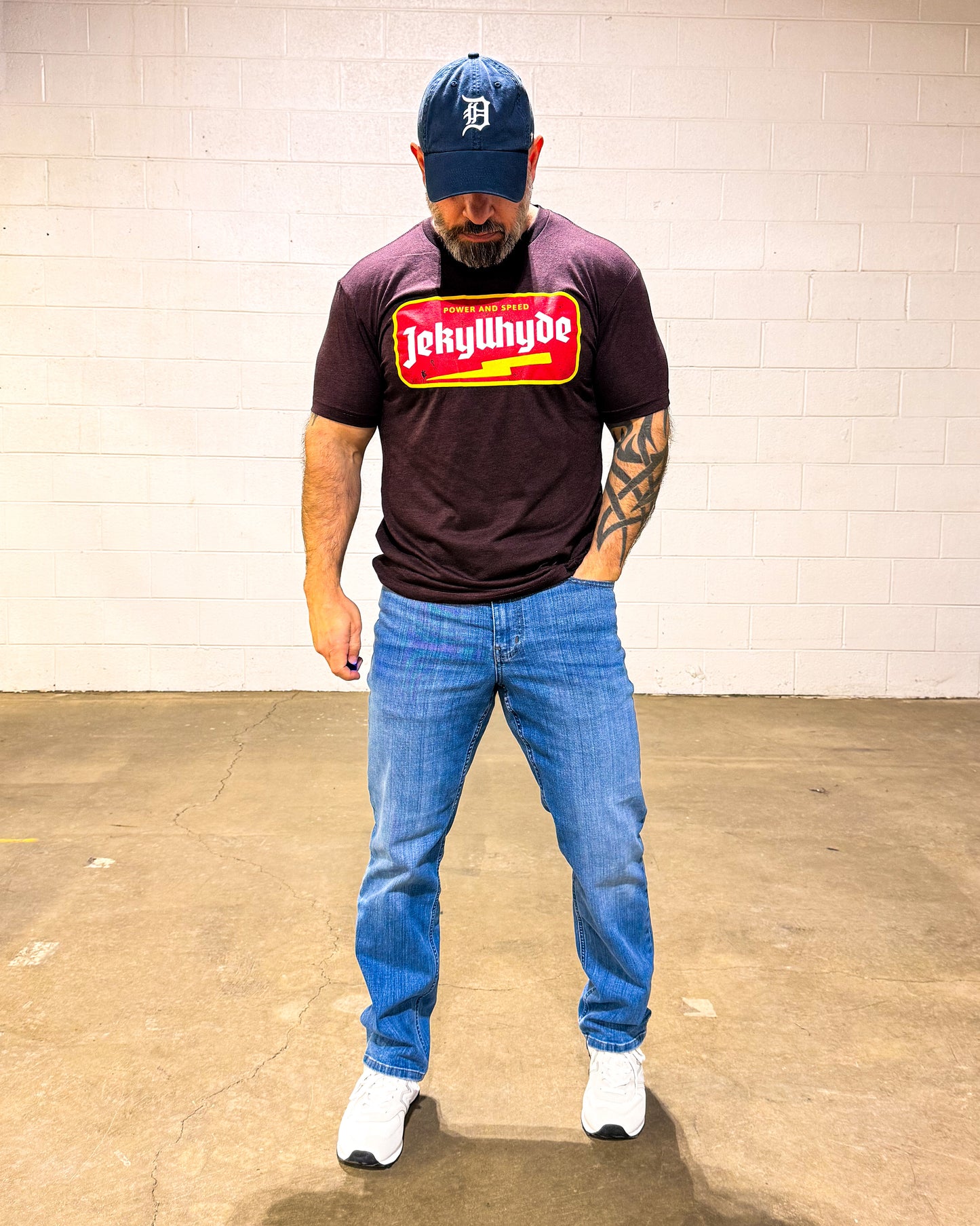 man standing looking at the ground in a maroon tshirt