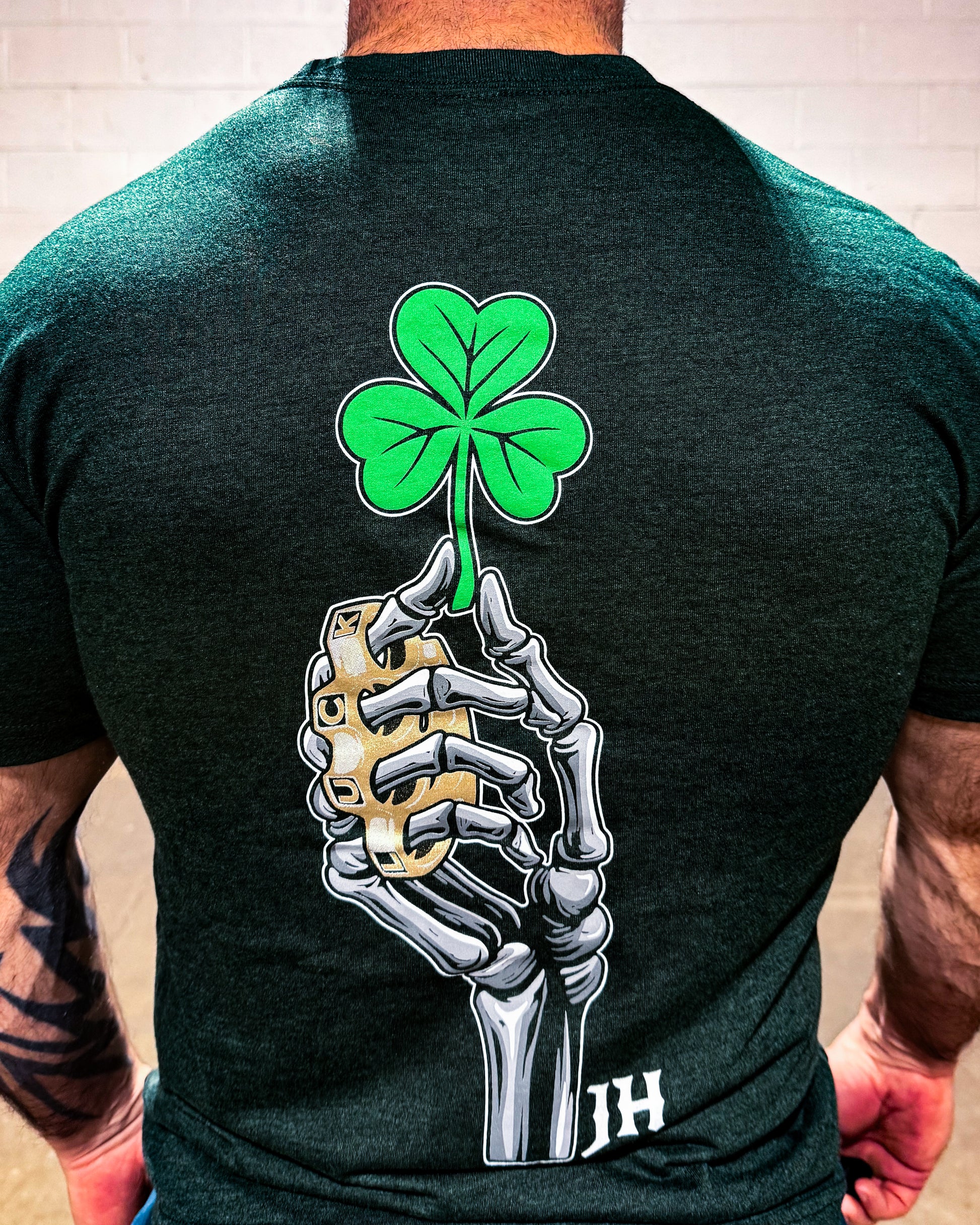Person wearing a black t-shirt with a skeleton hand holding a four-leaf clover design on the back.