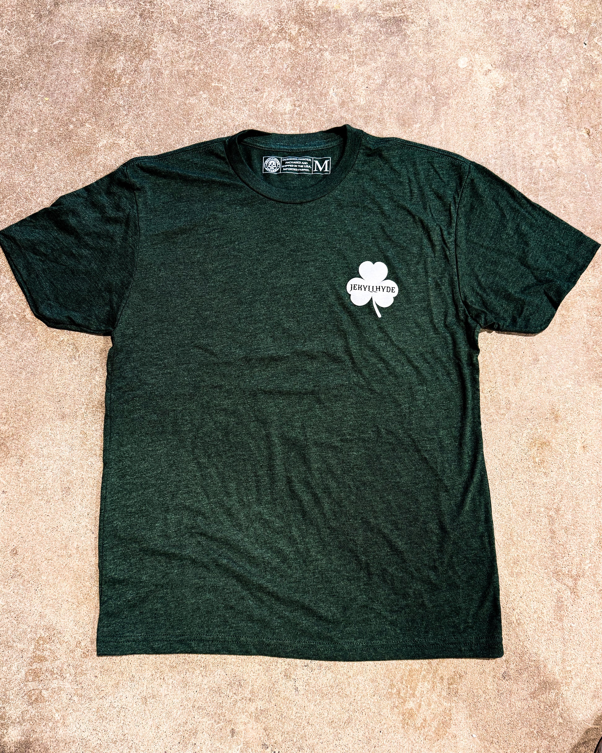 Green t-shirt with a white shamrock logo on a beige surface