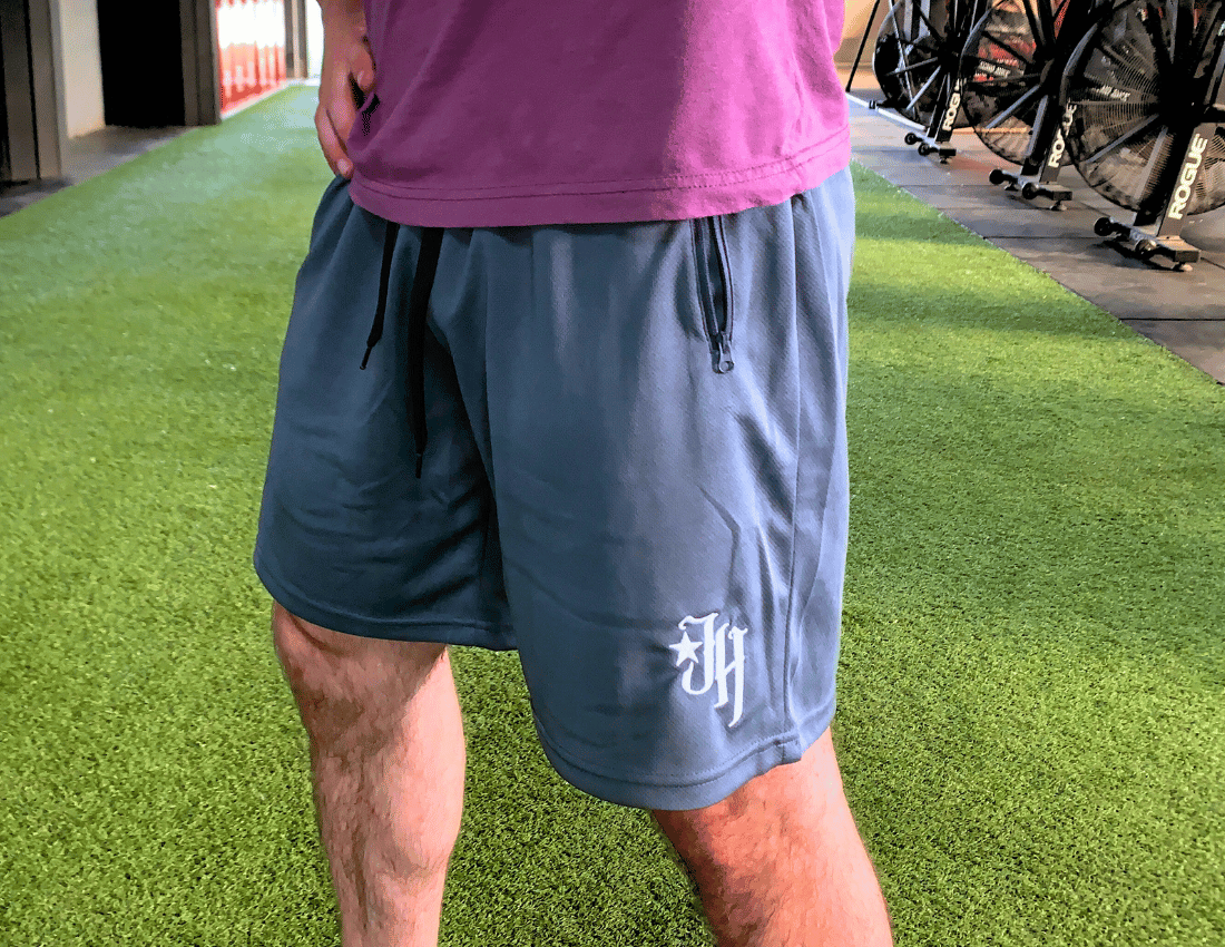 Grey shorts on a man standing on turf. 