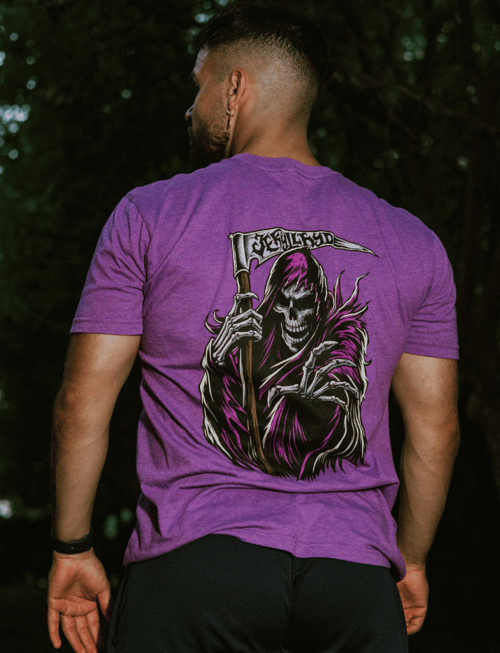 Man standing away from the camera wearing a purple shirt with a grim reaper on the back. 