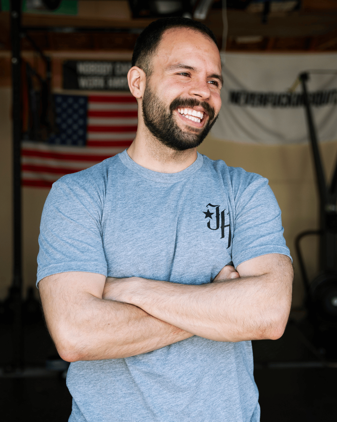 Man smiling wearing a grey shirt with a JH logo on the left chest. 