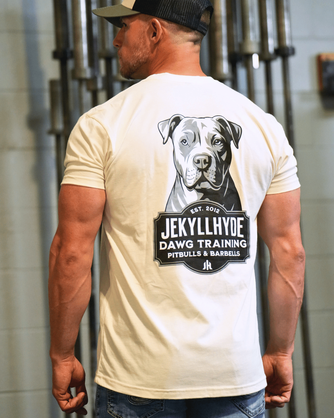 man standing in front a barbells wearing a pitbull tshirt. 