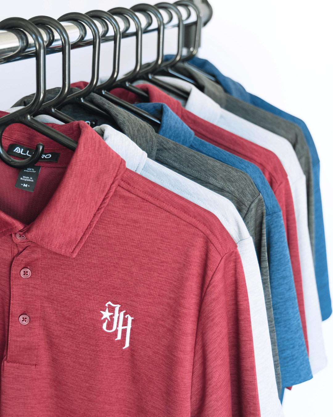 Red polo shirt with a logo on a rack of other shirts