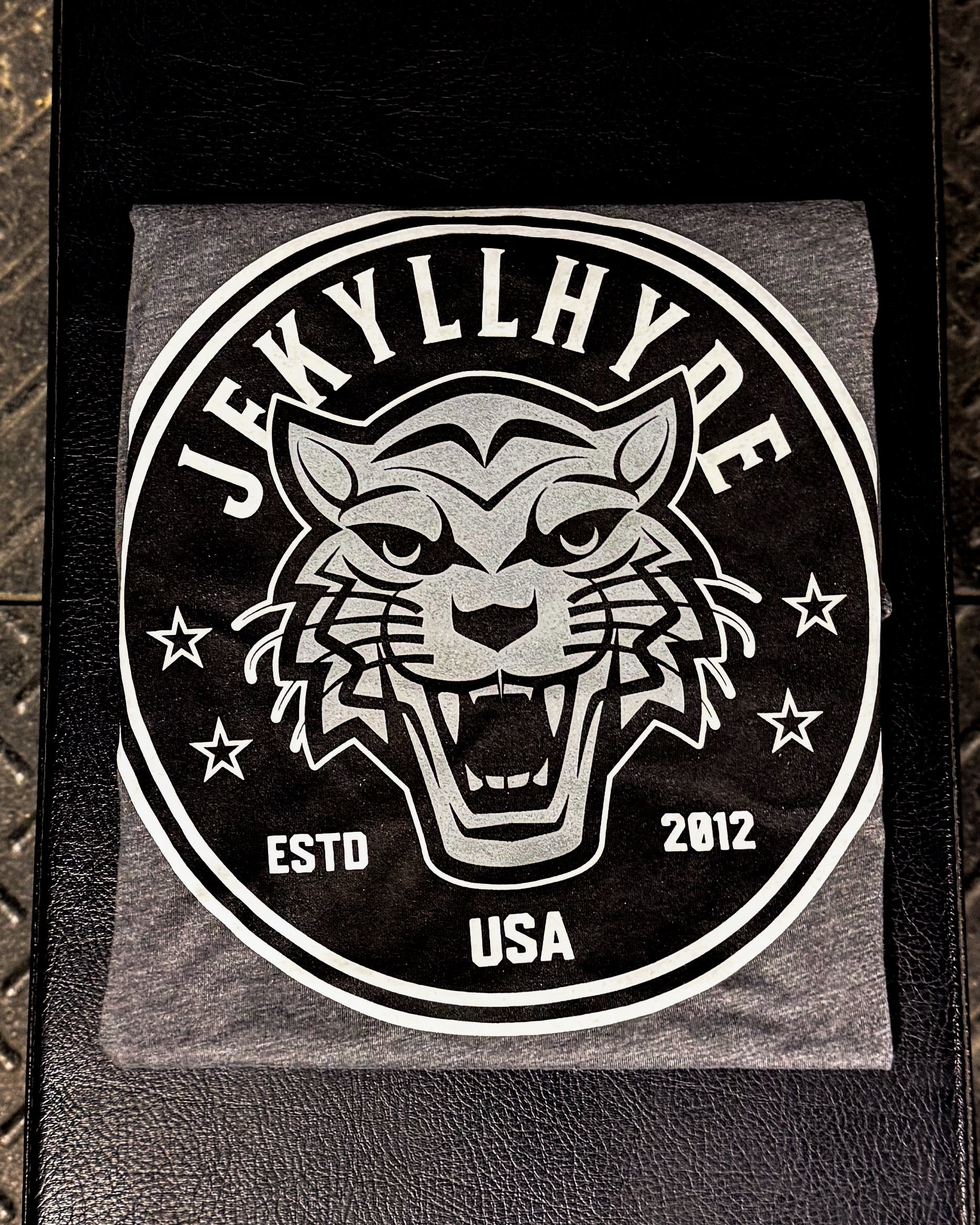 JekyllHyde grey t-shirt with Wildcat logo on a leather surface