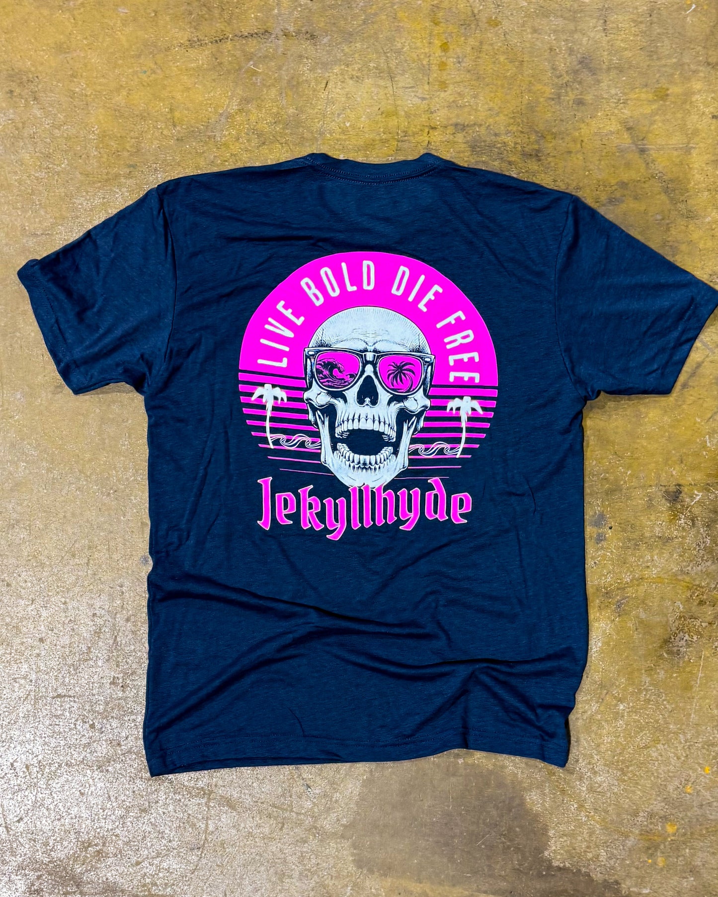 Navy blue t-shirt with a skull graphic and 'Live Bold Die Free' text on a textured yellow background