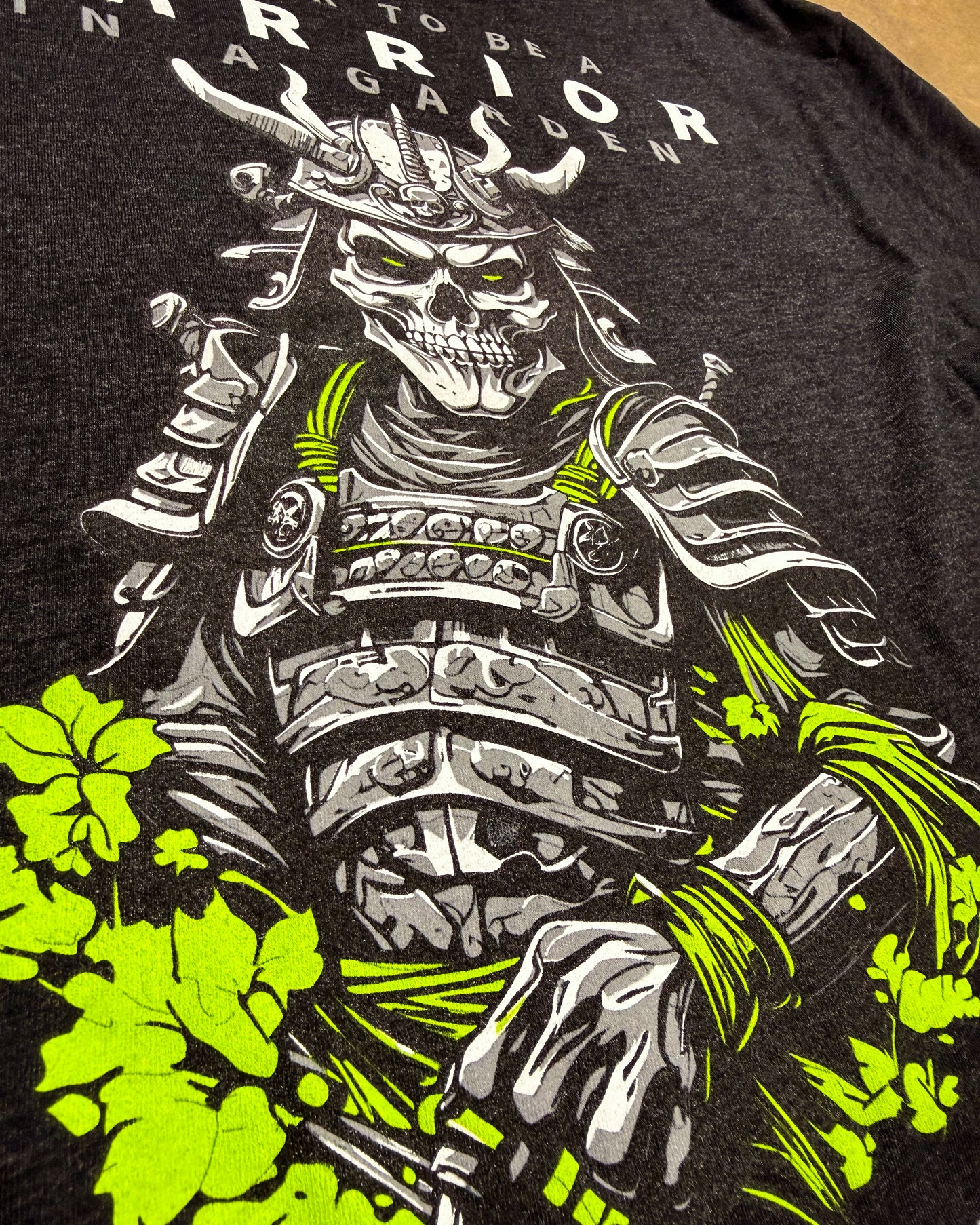 T-shirt with a graphic of a warrior skeleton in armor and green leaves on a black background.
