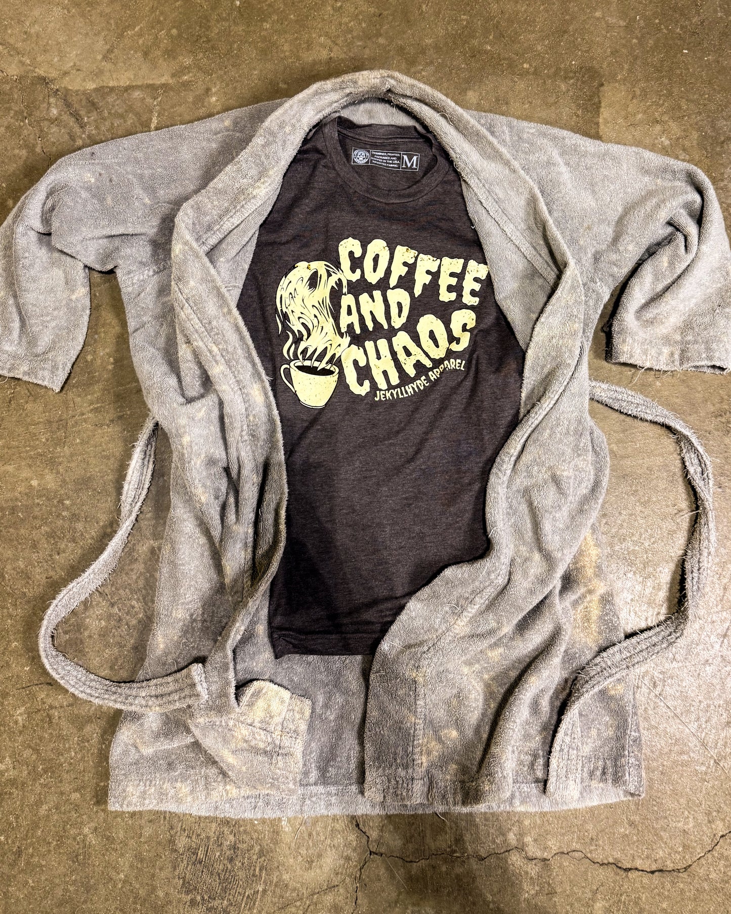 Black t-shirt with 'Coffee and Chaos' text on a gray sweater over a brown background