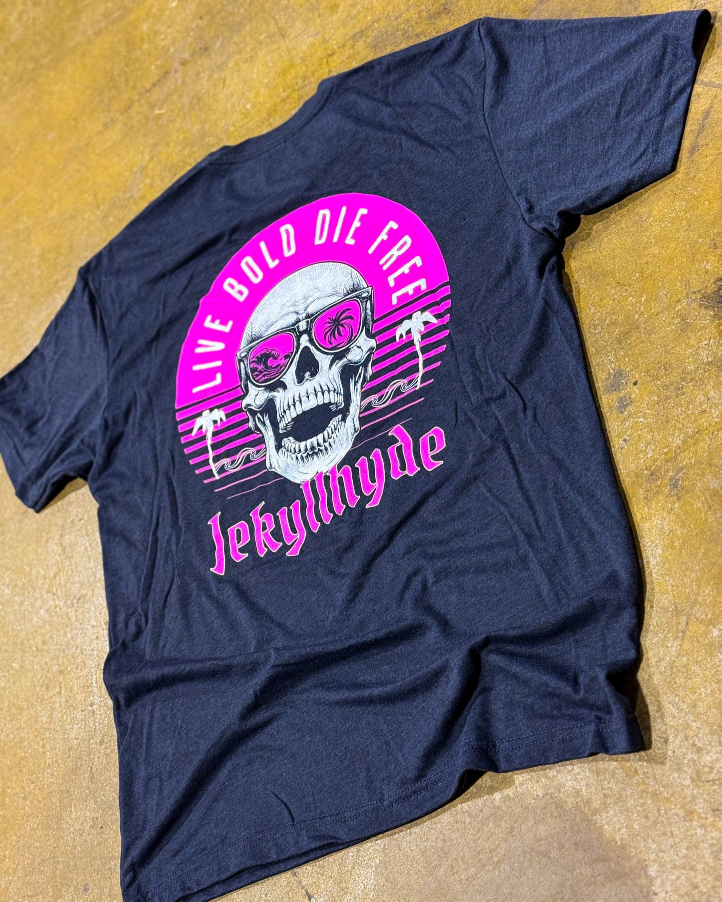 Navy blue t-shirt with a pink and white graphic design featuring a skull and text on a yellowish surface.