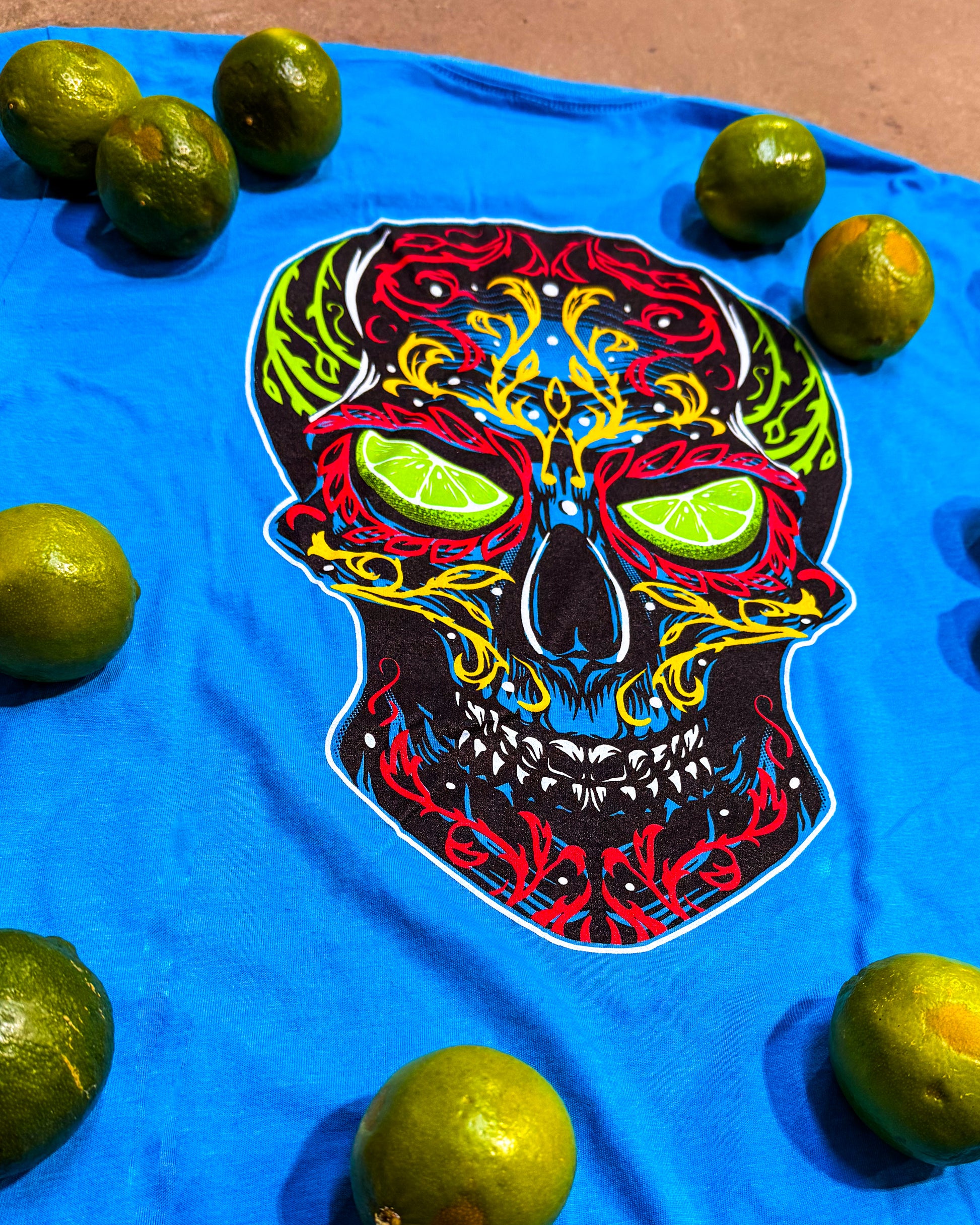 Colorful skull design on a blue t-shirt with limes around it