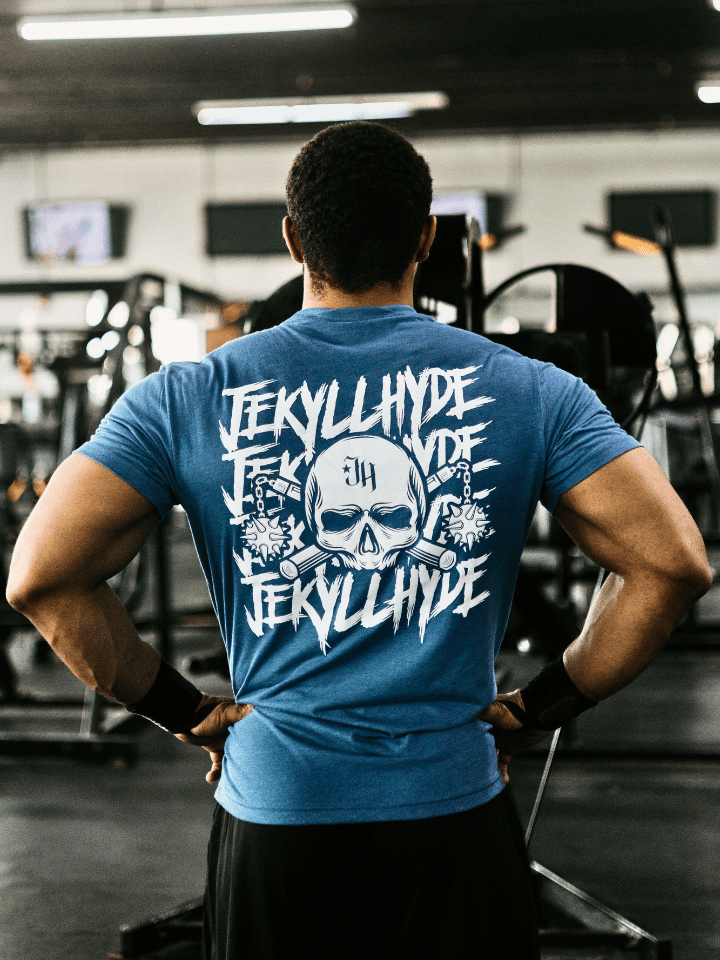 Man in a gym wearing a blue shirt with a skull and mace on it. 