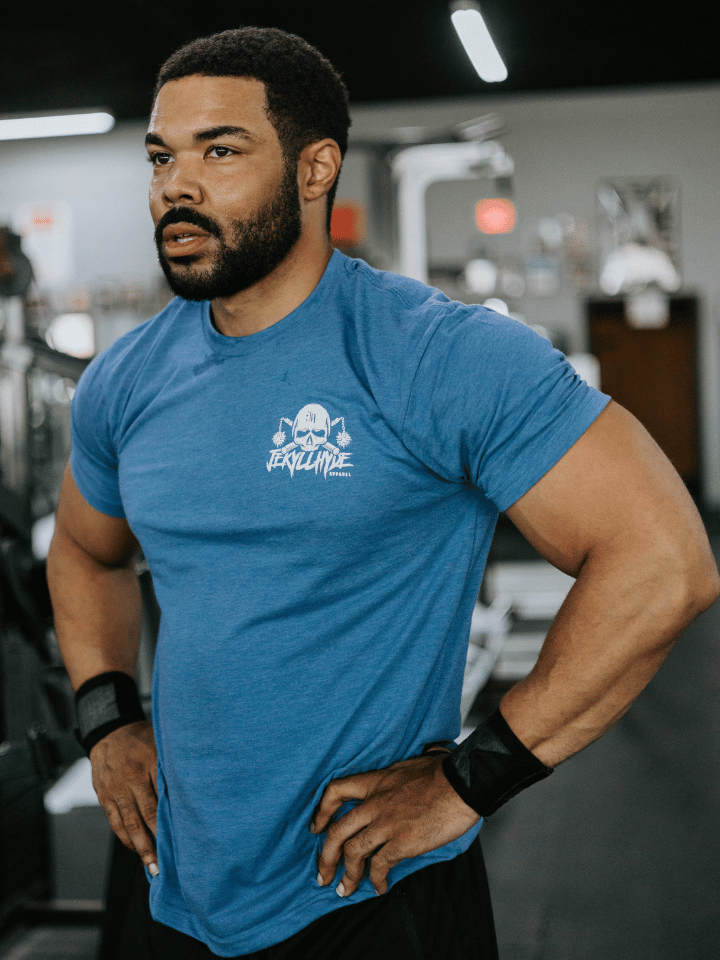Man looking past the camera wearing a blue shirt with a jekyllhyde logo on the left chest. 