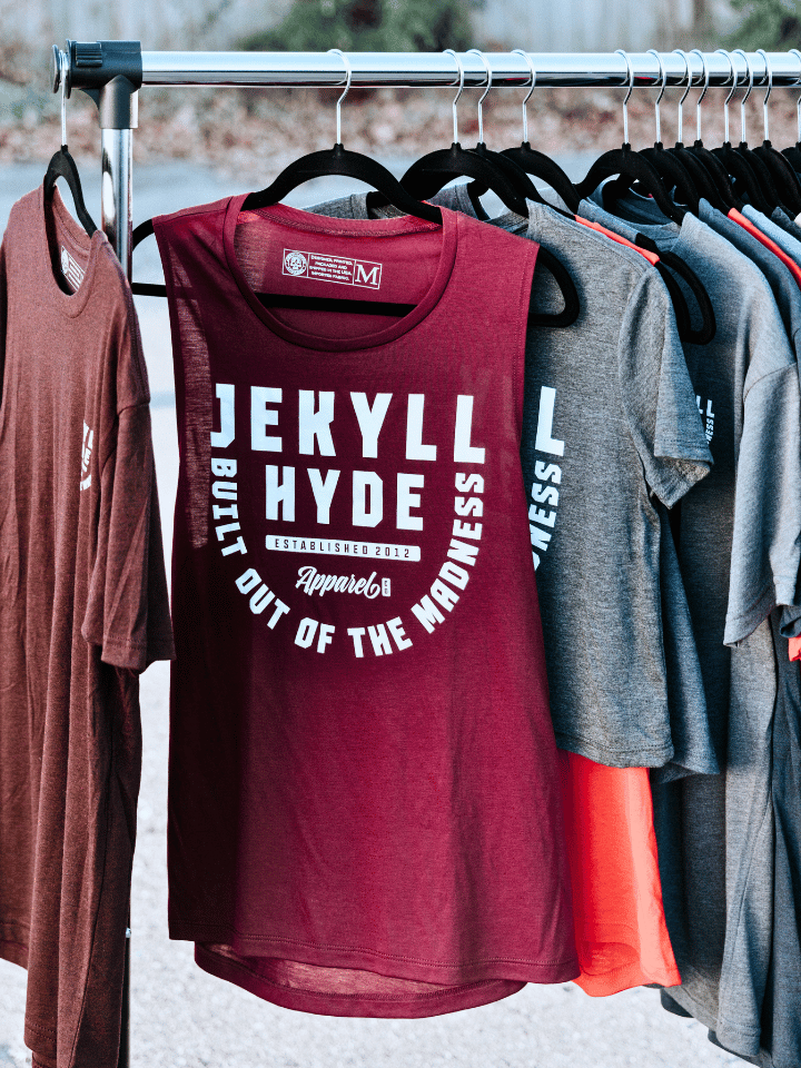 A maroon muscle tank handing on a clothes rack with other clothing items. 