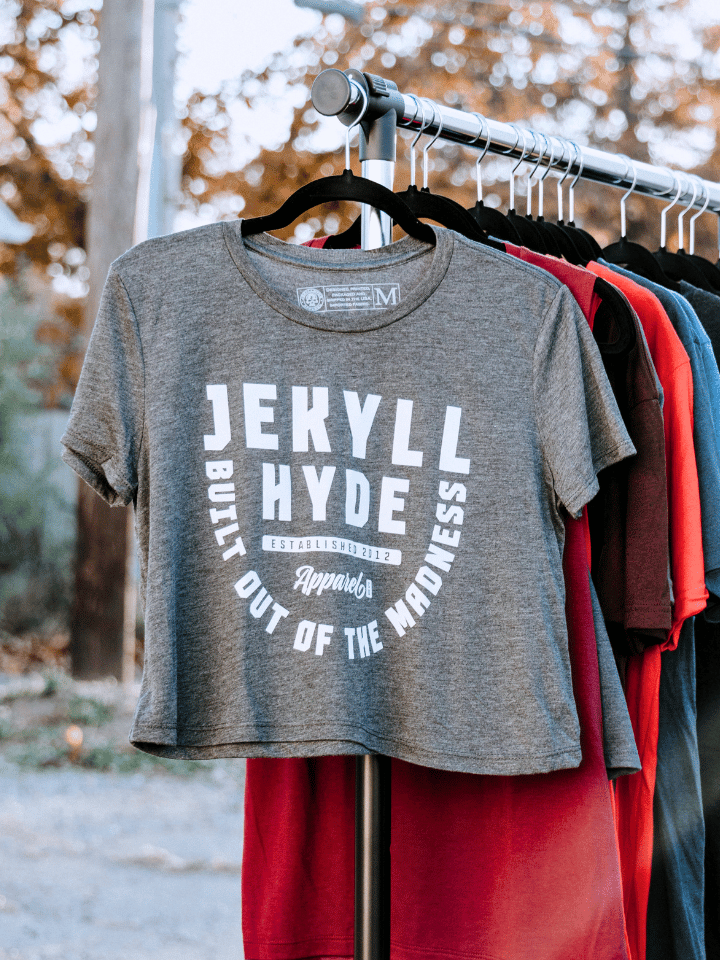 A grey crop top hanging on a rod with other clothing items. 
