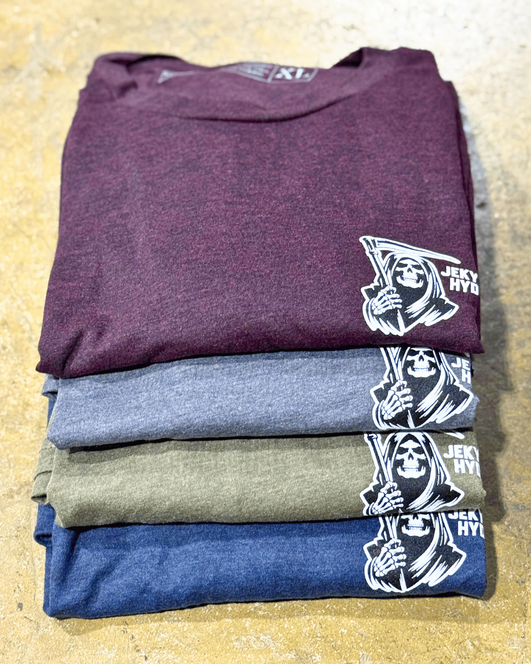 Stack of folded t-shirts with a logo on a textured surface