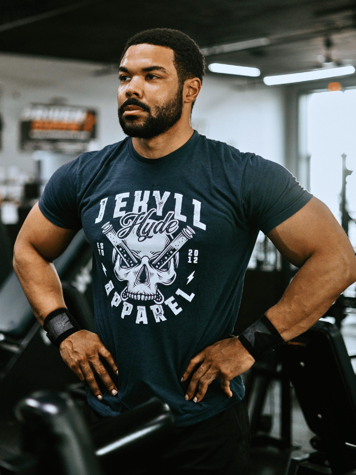 Man standing with his hand on his hips wearing a blue shirt with a skull on the front. 