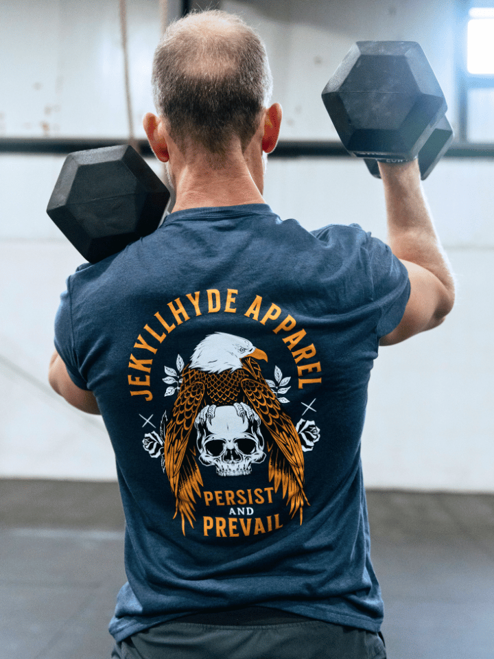 Man using dumbbells wearing a navy shirt with an eagle and skull on it. 