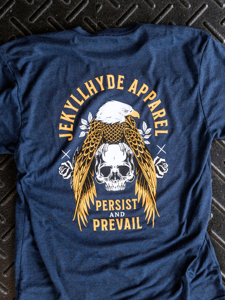 Navy tshirt with an eagle and skull on it laying on the ground. 