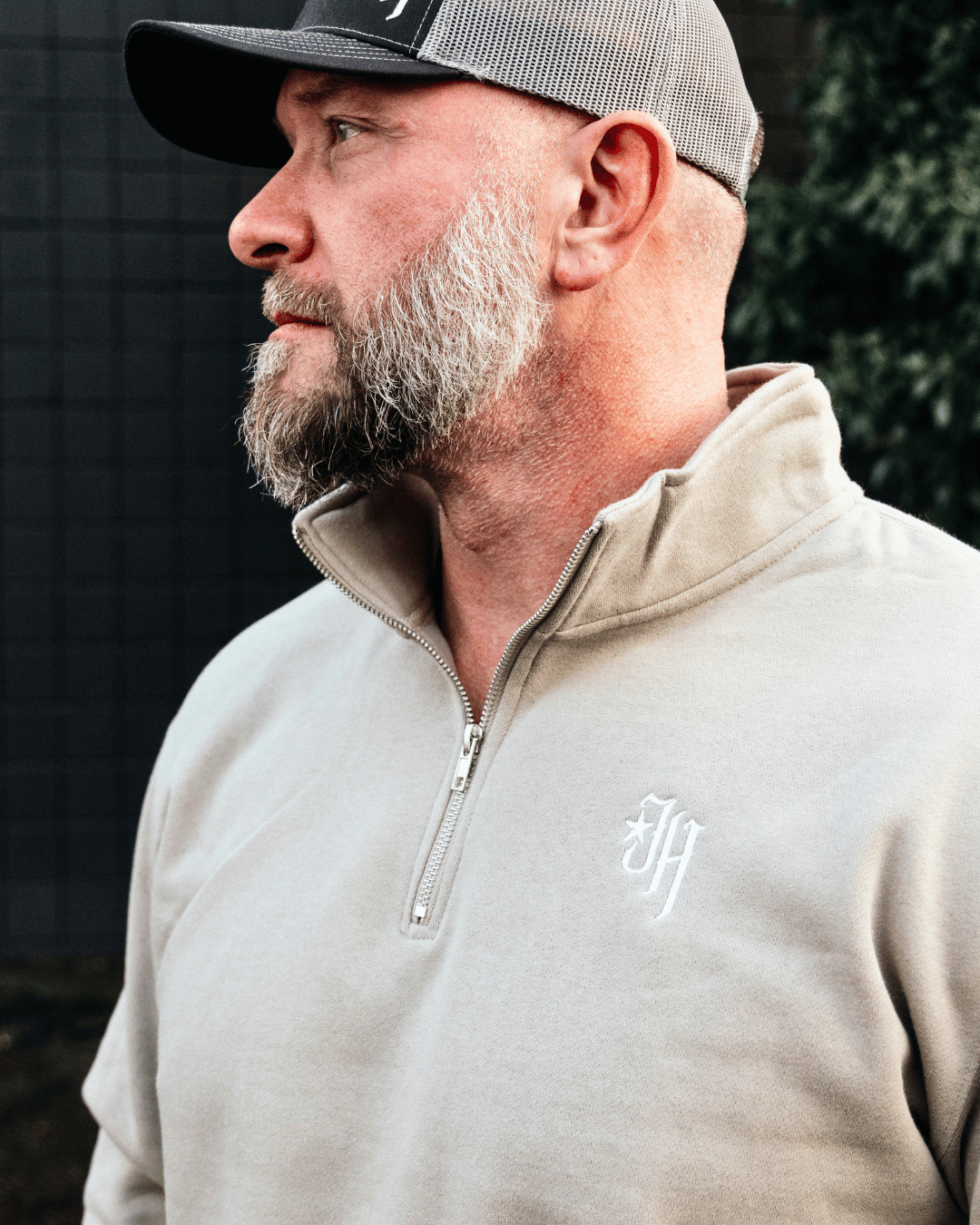 Man looking away in a tan quarter zip sweater. 