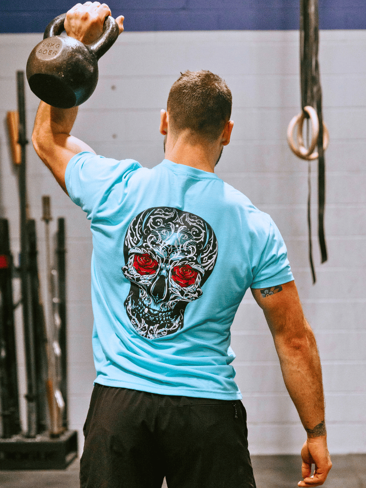 Man using a kettlebell wearing a sugar skull tshirt. 