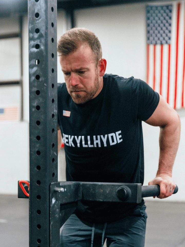 Man doing dips with an american flag in the background. 