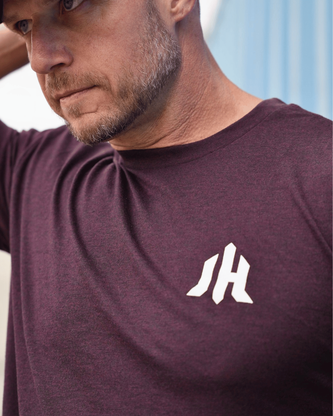 Close up of a maroon shirt with the letters JH on the left chest. 