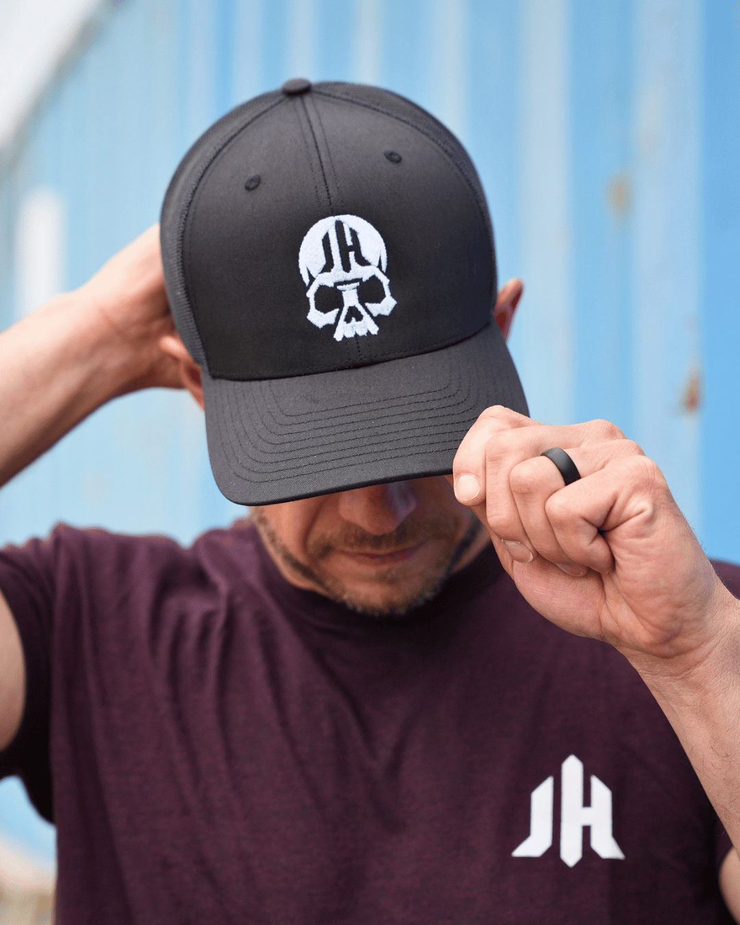 Man adjusting a black hat with a skull on it.