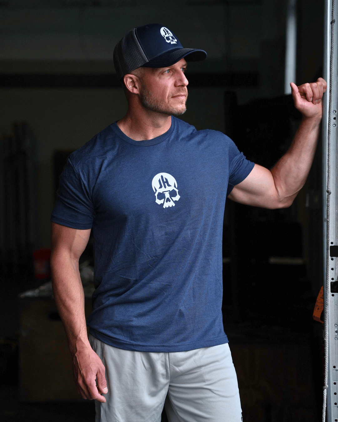 Man standing at a bay door wearing a navy shirt with a skull on the chest. 