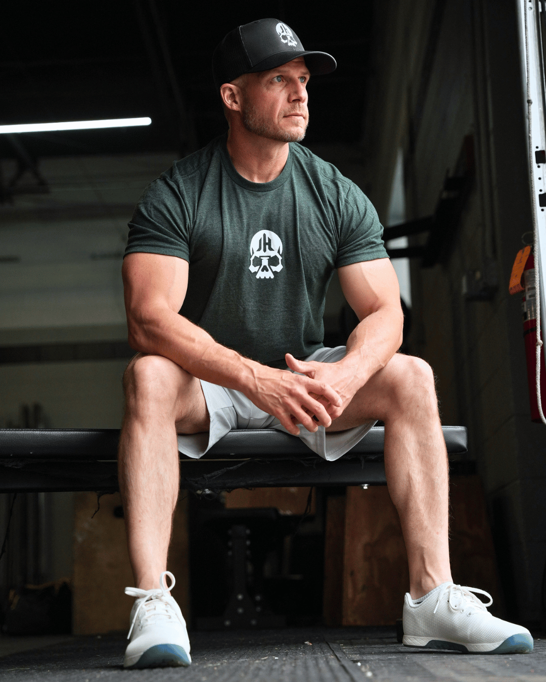 Man sitting on a bench wearing a green shirt with a skull on the chest. 