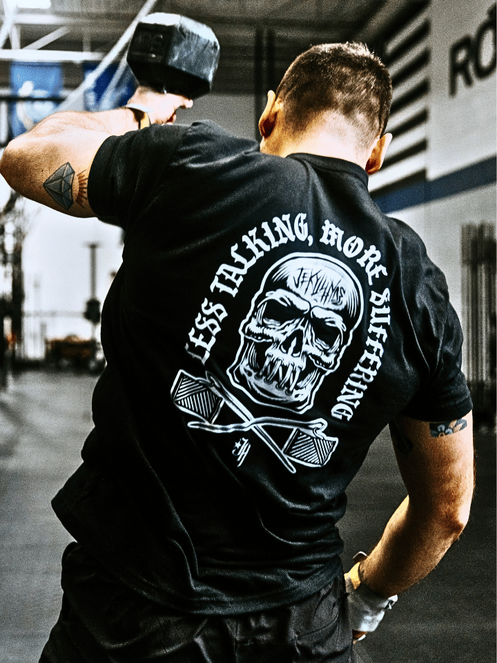 Man with a dumbbell in a black shirt with a skull that has its mouth sewn shut.