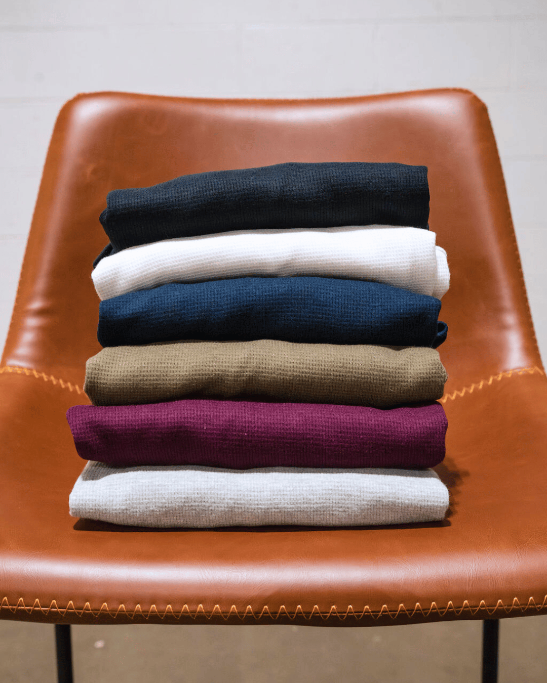 6 folded thermals set on a chair. 