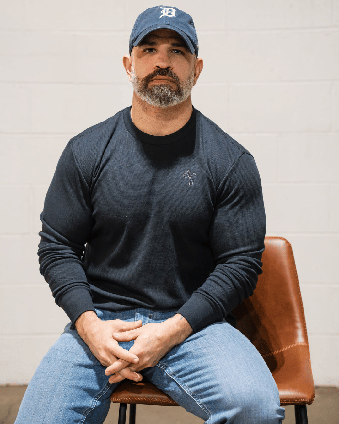 Man sitting in a chair wearing a black thermal and a hat. 