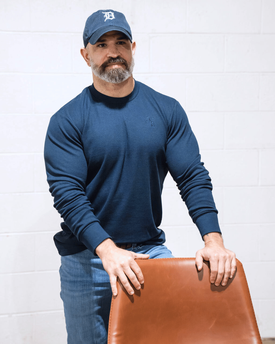 A man standing behind a chair wearing a navy thermal. 