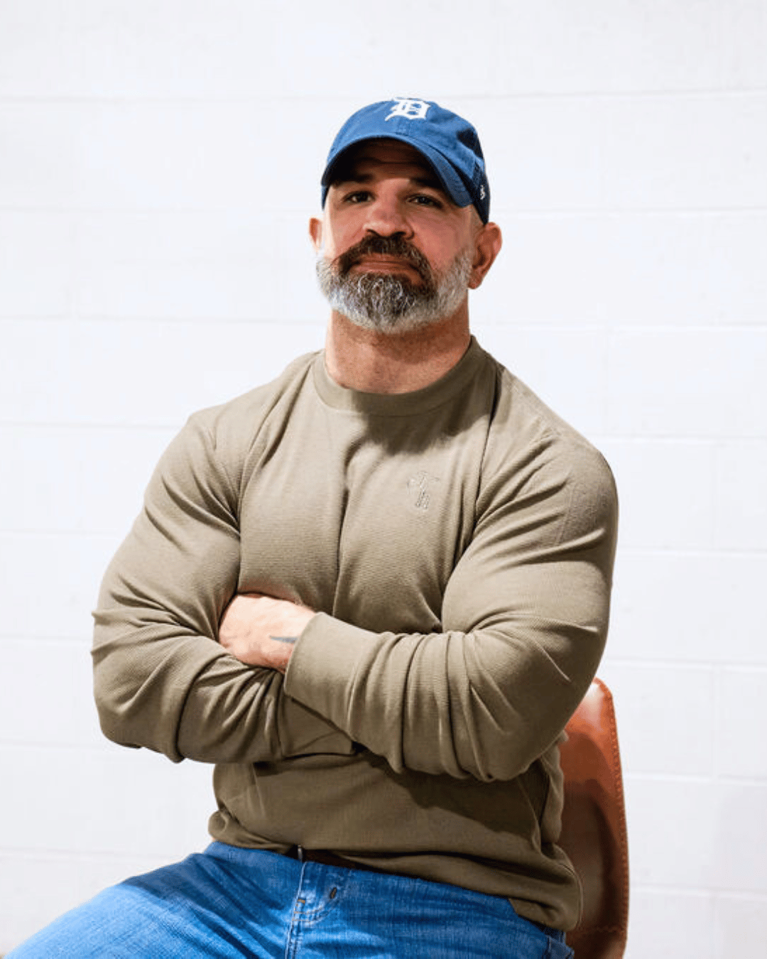 A bearded man with his arms crossed wearing a green thermal. 