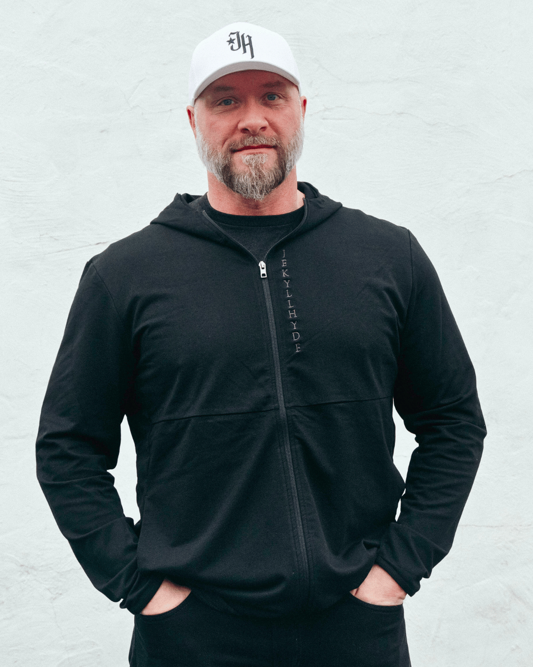 Muscular man standing in a black jacket with white background. 