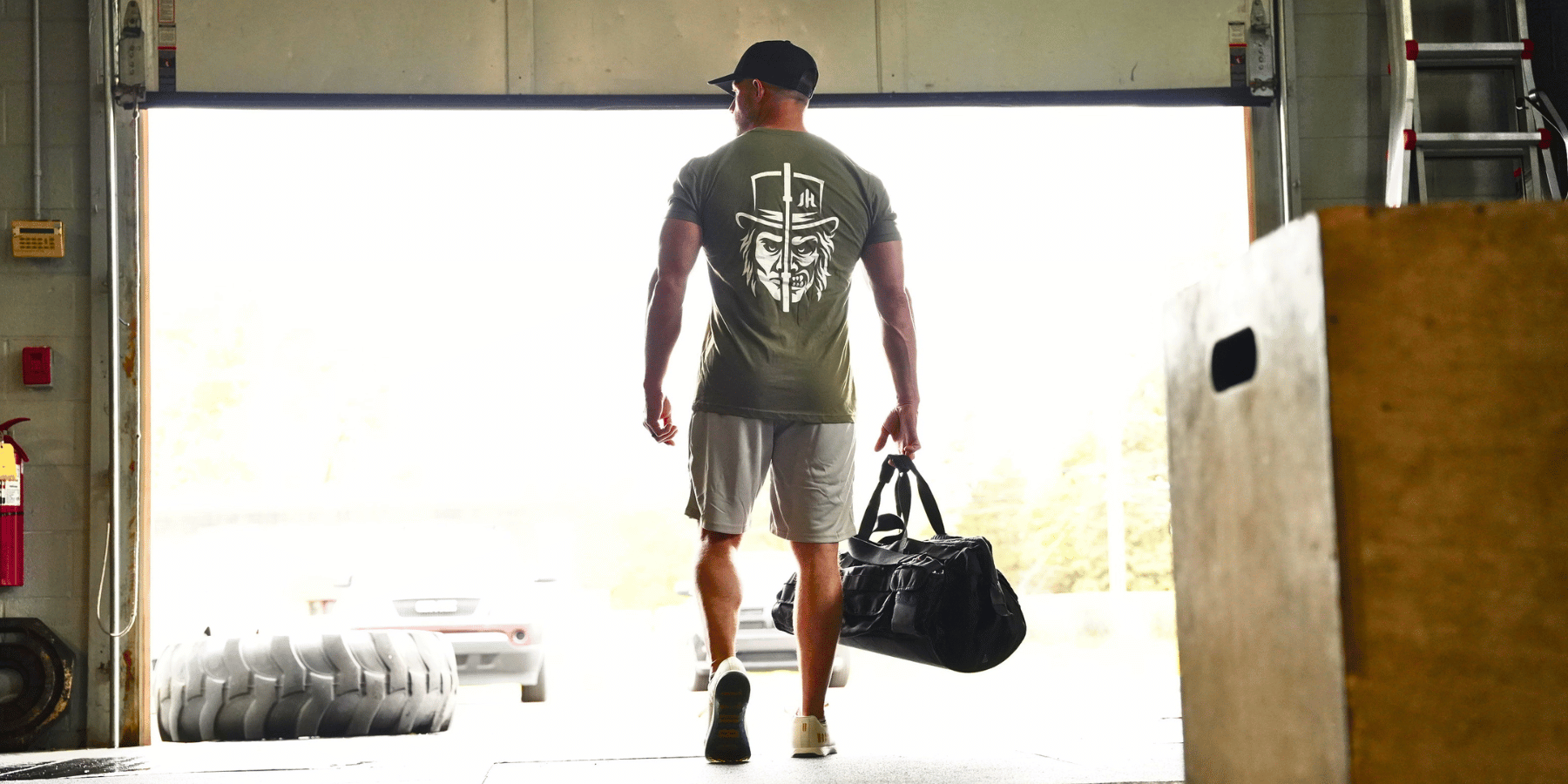 Man walking out of the gym holding a gym bag wearing a two face t-shirt design. 