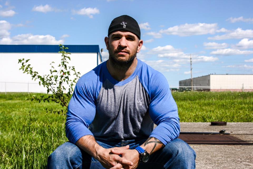 Man sitting down in a grey and blue raglan. 