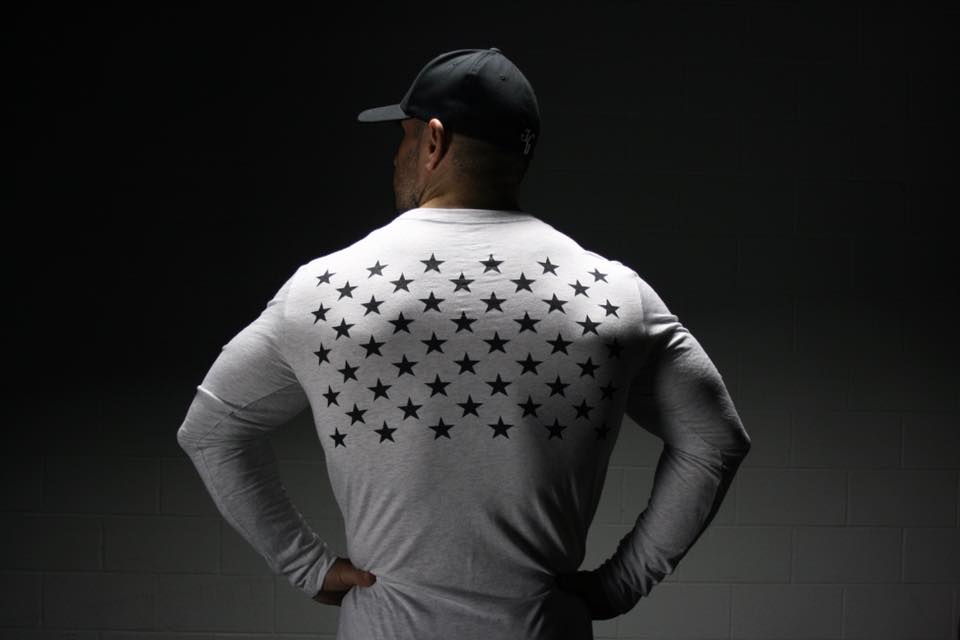 Man in white, long sleeve shirt looking away from camera with stars on the back of the shirt. 