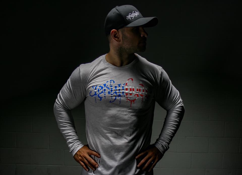 Man lookin away wearing a white, long sleeve shirt with jekyllhyde logo on chest. 