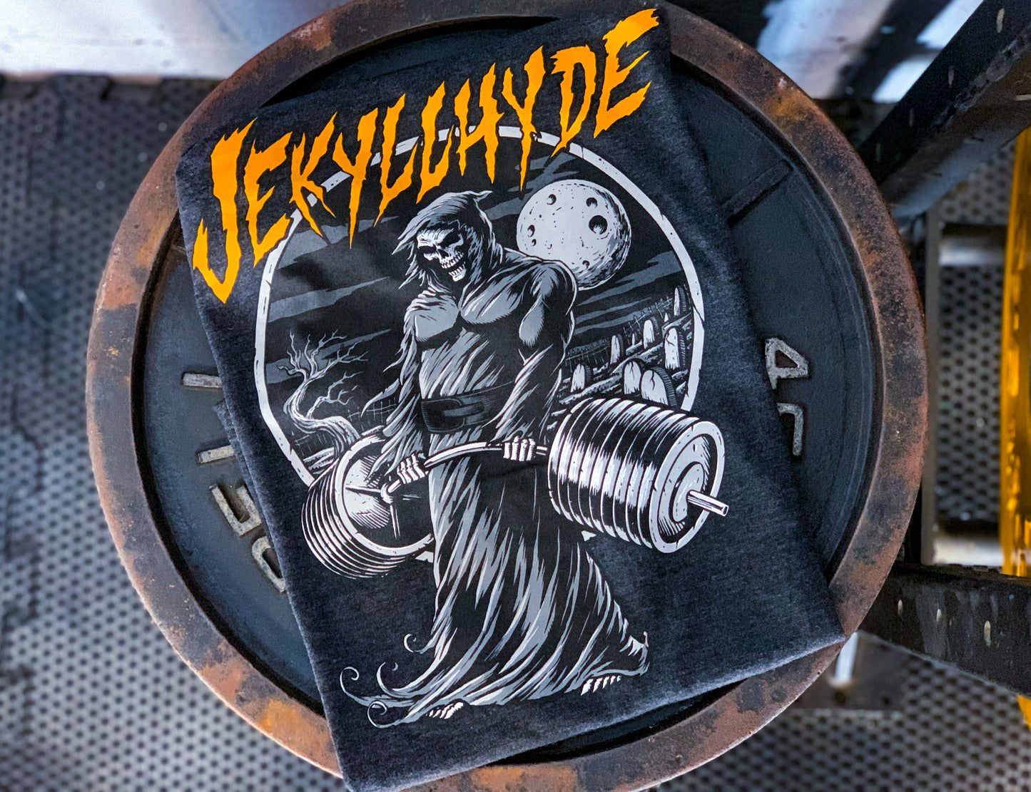 Black shirt on a rusted weight with a deadlifting grim reaper. 