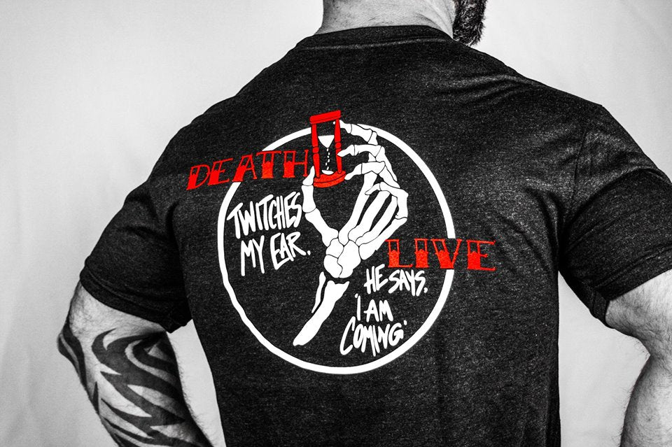 Man wearing a black tshirt with skeleton hand holding a hour glass. 
