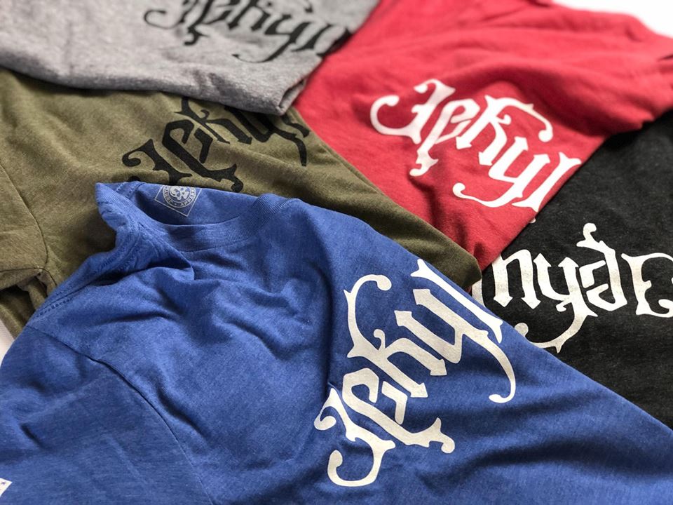 A bunch of tshirts of different colors laying on the floor together. 