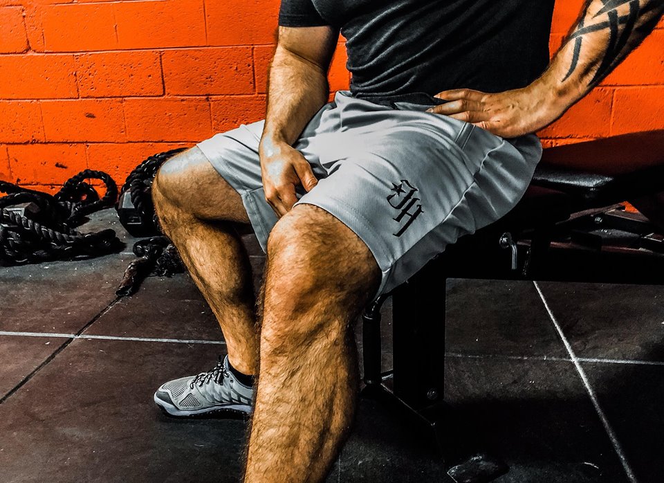 Grey shorts on a man sitting on a exercise bench. 