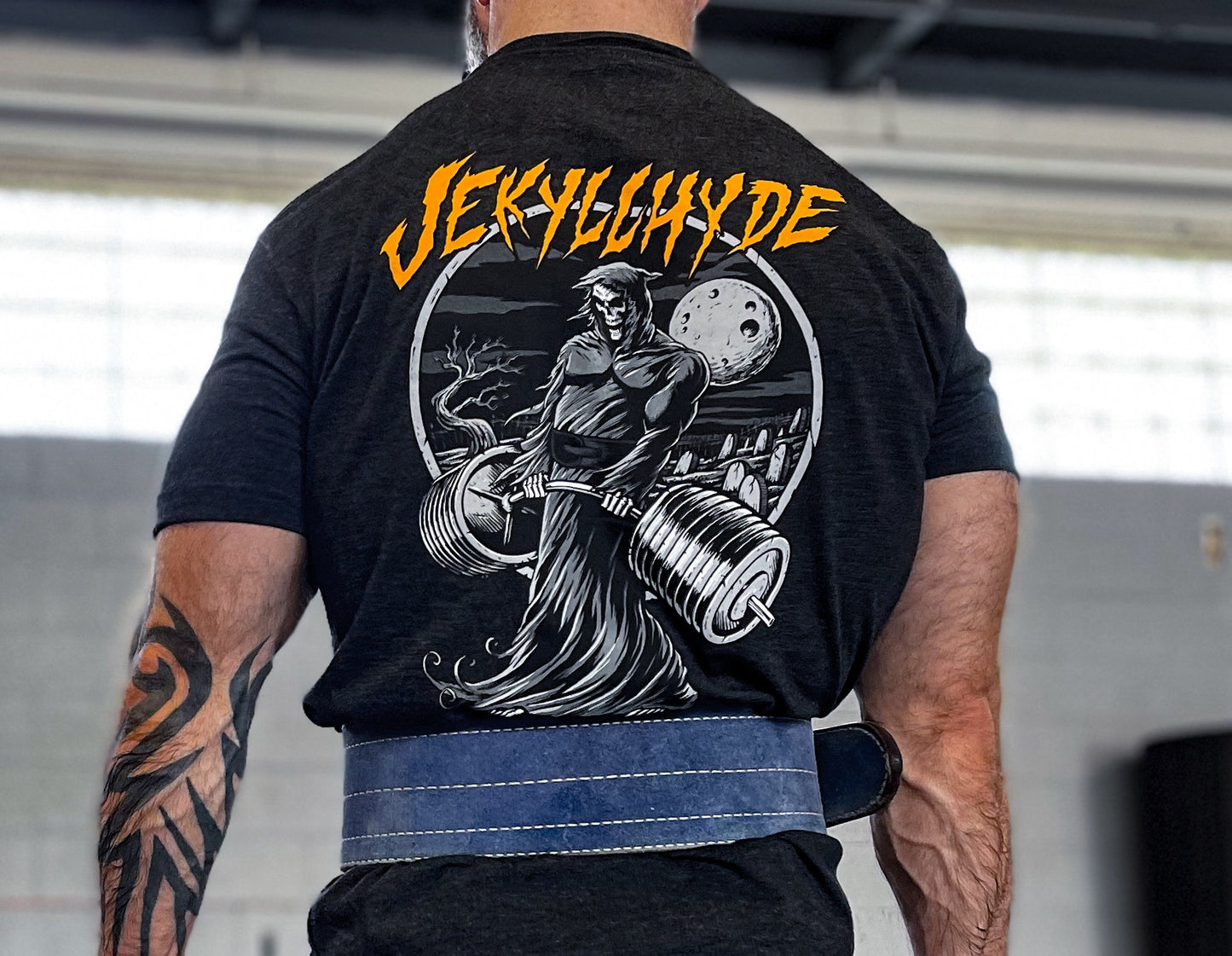 Man wearing a lifting belt wearing a black tshirt with a deadlifting grim reaper. 